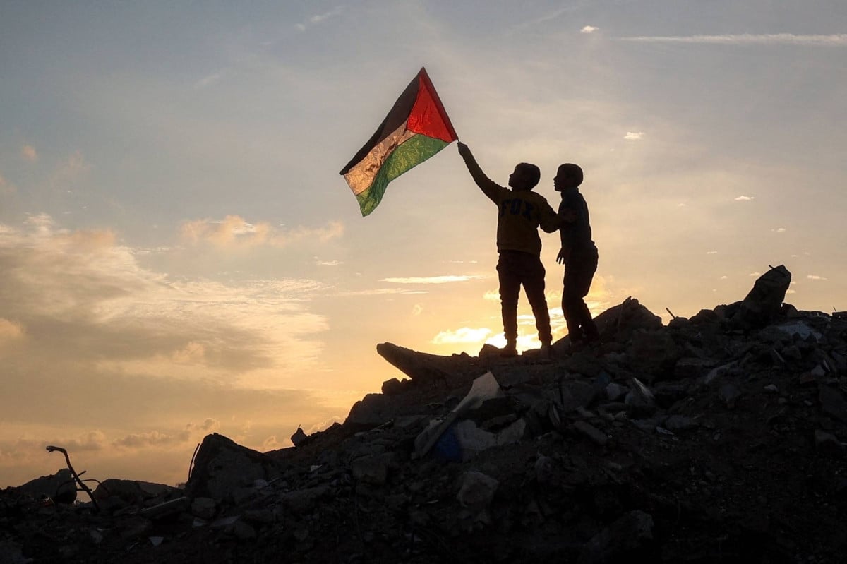 a boy runs with a palestinian flag atop a mound of rubble at a camp in bureij central gaza strip on friday photo afp