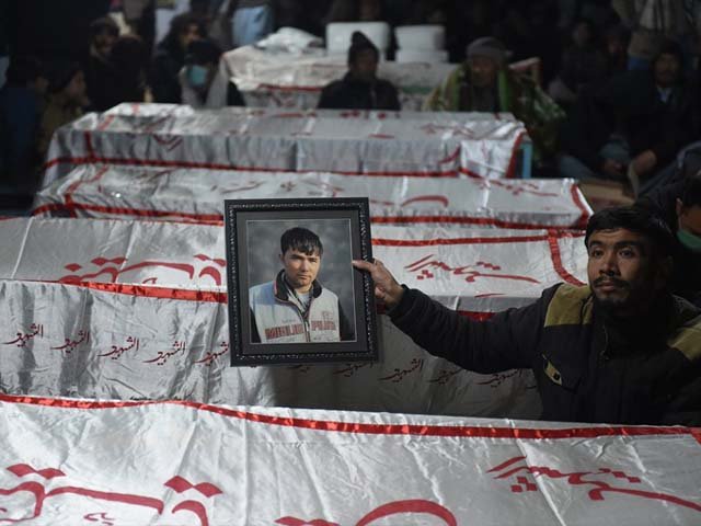 a mourner from the shia hazara community holds a photograph of a victim near the coffins of other miners who were killed in an attack by gunmen photo afp file
