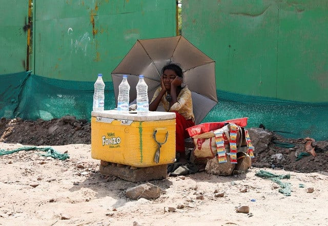 a girl selling water uses an umbrella to protect herself from the sun as she waits for customers on a hot summer day in new delhi india april 27 2022 photo reuters a girl selling water uses an umbrella to protect herself from the sun as she waits for customers on a hot summer day in new delhi india april 27 2022 photo reuters