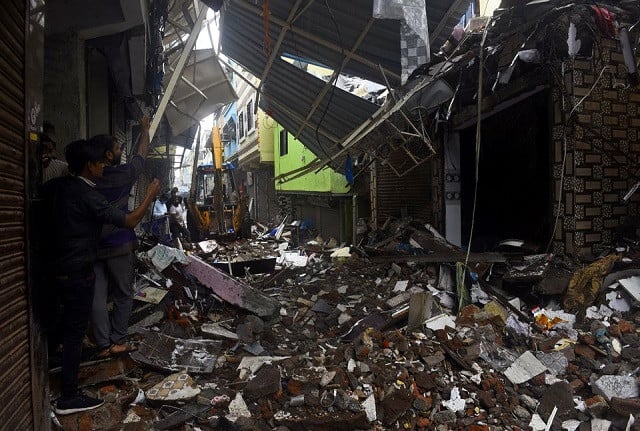 People use their mobile phones to take pictures of a collapsed building following rains in Mumbai, India, July 23, 2021. PHOTO: REUTERS