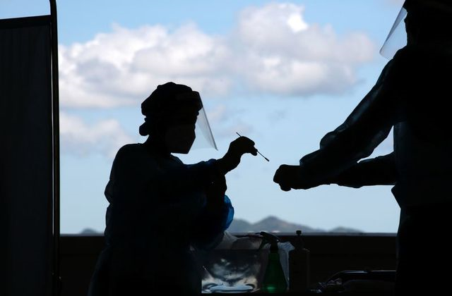 a health worker puts a swab sample from a taxi driver into a container for covid 19 test at a makeshift testing station in a parking lot following the coronavirus disease covid 19 outbreak in hong kong china july 27 2020 photo reuters