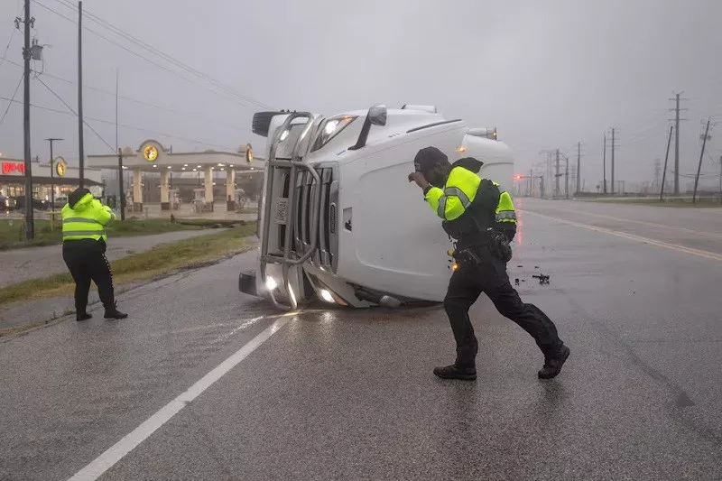 police officers struggle with fierce winds from hurricane beryl as they search an overturned semi trailer truck for occupants in freeport texas us july 8 2024 photo reuters