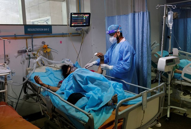 a medical worker tends to a patient suffering from coronavirus disease covid 19 as a syringe infusion pump donated by france is seen next to his bed inside the emergency room of safdarjung hospital in new delhi india may 7 2021 photo reuters