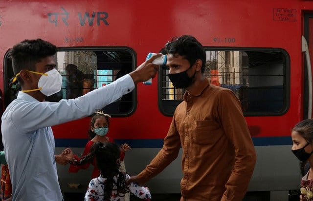 a healthcare worker checks the temperature of a passenger upon his arrival at a railway station amidst the coronavirus disease covid 19 pandemic in mumbai india november 29 2021 photo reuters a healthcare worker checks the temperature of a passenger upon his arrival at a railway station amidst the coronavirus disease covid 19 pandemic in mumbai india november 29 2021 photo reuters