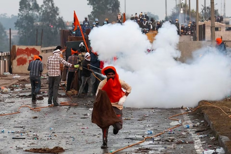 A protester runs from rip gas, as farmers impetus towards New Delhi, during Shambhu, India, Feb 14, 2024. PHOTO: REUTERS