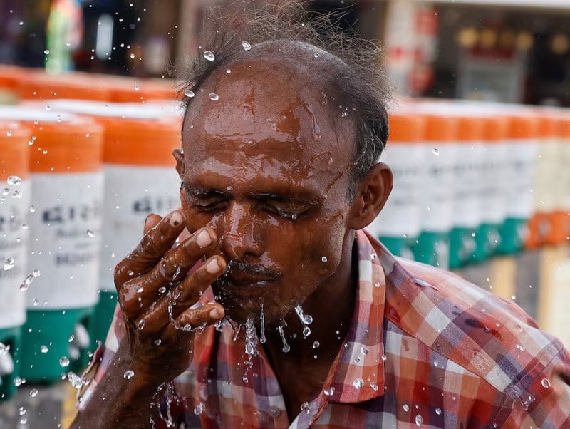 A man sprays cold water on his face from a water jar during a heatwave in Ahmedabad, India, May 29, 2024. PHOTO: REUTERS