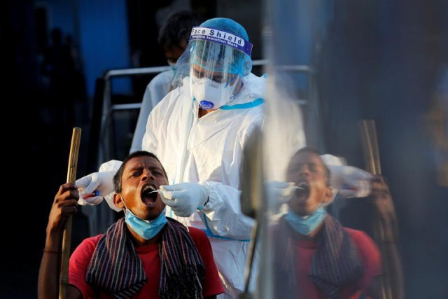 a healthcare worker collects a coronavirus disease covid 19 test swab sample from a man at a temporary shelter for homeless people in new delhi india march 31 2021 photo reuters file