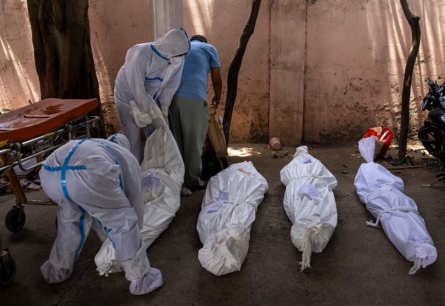 healthcare workers place the body of a person who died due to the coronavirus disease covid 19 on the ground for cremation at a crematorium ground in new delhi india april 28 2021 photo reuters