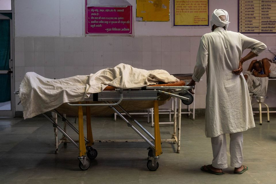 a man stands next to the body of his wife who died due to breathing difficulties inside an emergency ward of a government run hospital amidst the coronavirus disease covid 19 pandemic in bijnor uttar pradesh india may 11 2021 photos reuters