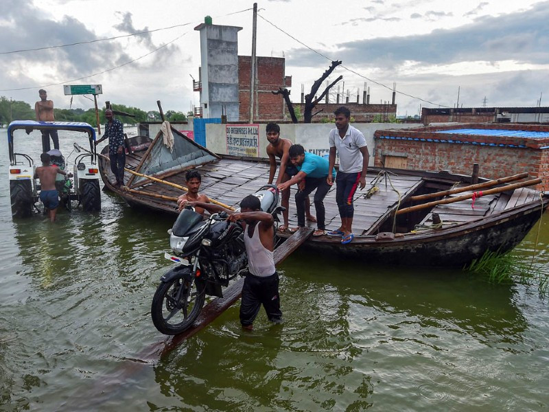 villagers use a boat to commute at a waterlogged area caused by floodwaters after a rise in water level of river yamuna following monsoon rains at badara sanuti village near allahabad on august 20 2022 photo afp file