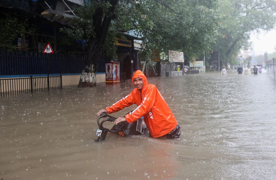 a man wades through a flooded street with his bike amidst heavy rainfall in mumbai india july 5 2022 photo reuters