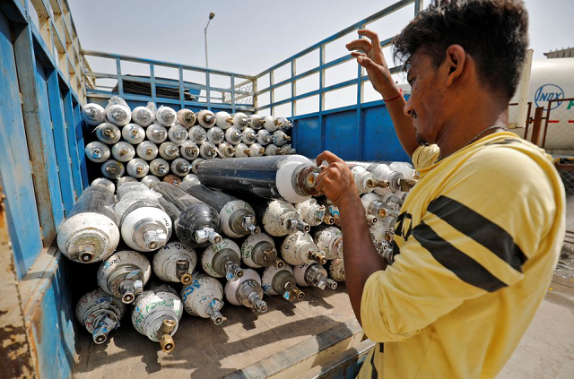 a worker loads empty oxygen cylinders onto a supply van to be transported to a filling station at a covid hospital in ahmedabad india photo reuters file