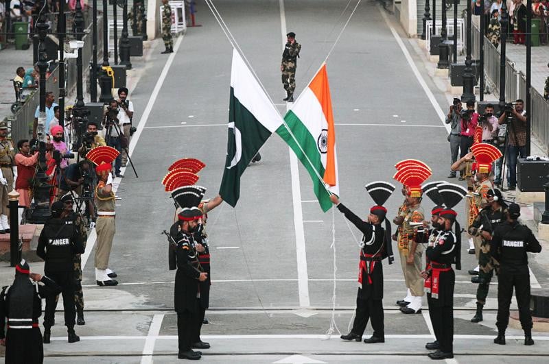 pakistani rangers wearing black uniforms and indian border security force bsf officers lower their national flags during parade on the pakistan s 72nd independence day at the pakistan india joint check post at wagah border near lahore photo reuters file