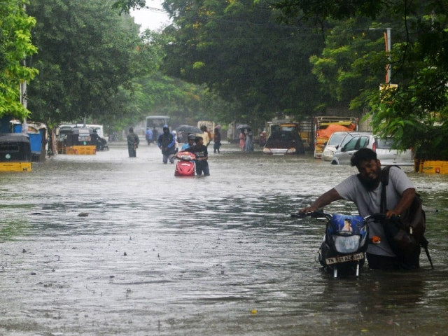 in this file photo commuters push their two wheelers through a flooded street after heavy rain shower in chennai on november 7 2021 photo afp in this file photo commuters push their two wheelers through a flooded street after heavy rain shower in chennai on november 7 2021 photo afp