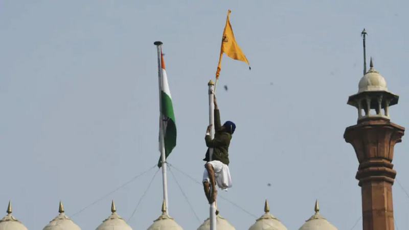 a protestor climbs atop the red fort to hoist a flag photo india today