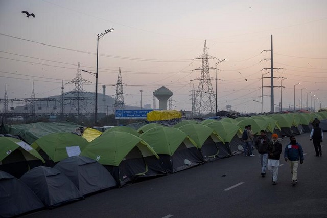farmers walk outside their tents at the site of a protest against new farm laws at the delhi uttar pradesh border in ghaziabad india january 11 2021 photo reuters