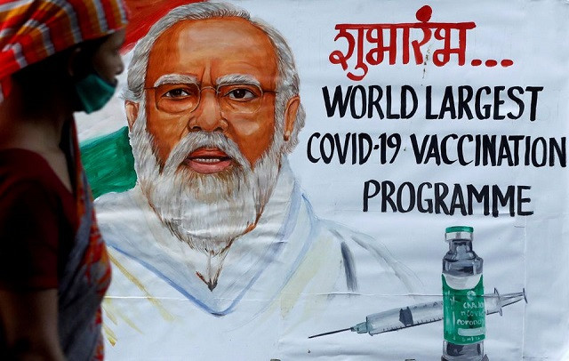 a woman walks past a painting of indian prime minister narendra modi a day before the inauguration of the covid 19 vaccination drive on a street in mumbai india january 15 2021 photo reuters