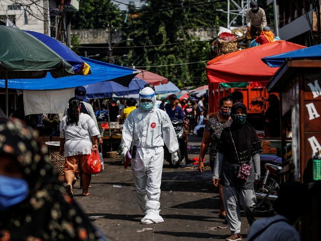 a healthcare worker wearing protective gear walks through a traditional market as swab samples are collected from vendors to be tested for the coronavirus disease covid 19 in jakarta indonesia photo reuters