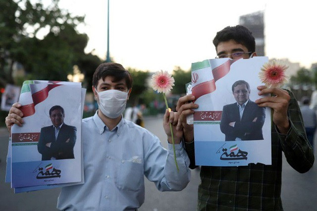 Supporters of presidential candidate Abdolnaser Hemmati hold posters of him in a street in Tehran, Iran June 16, 2021. PHOTO: REUTERS