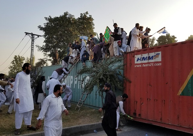 people climb over shipping containers as they try to go towards the french embassy during a protest in islamabad on friday photo reuters