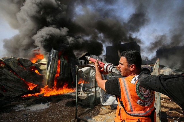 A Palestinian firefighter participates in efforts to put out a fire at a sponge factory after it was hit by Israeli artillery shells, according to witnesses, in the northern Gaza Strip May 17, 2021. PHOTO: REUTERS