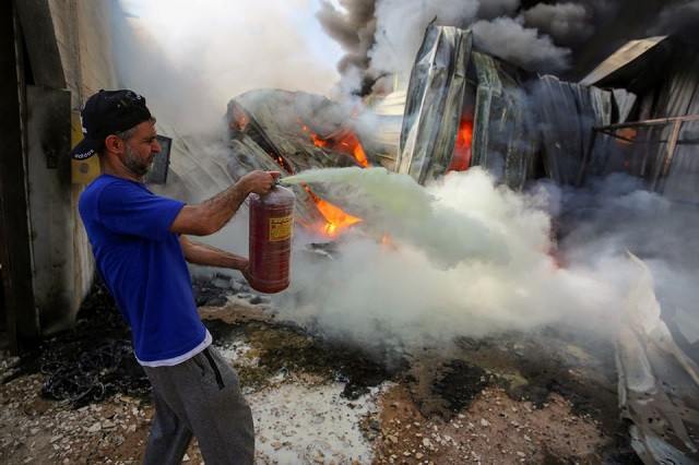 A Palestinian man puts out a fire at a sponge factory after it was hit by Israeli artillery shells, according to witnesses, in the northern Gaza Strip May 17, 2021. PHOTO: REUTERS