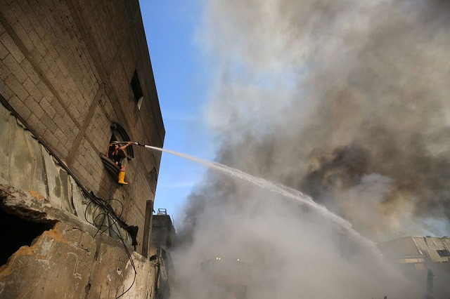 A Palestinian firefighter puts out a fire at a sponge factory after it was hit by Israeli artillery shells, according to witnesses, in the northern Gaza Strip May 17, 2021. PHOTO: REUTERS