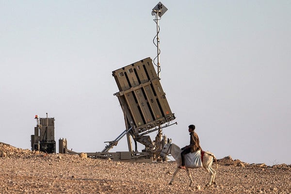 A boy rides a donkey near one of the batteries of Israel's Iron Dome missile defence system at a village not recognised by Israeli authorities in the southern Negev desert. PHOTO: AFP