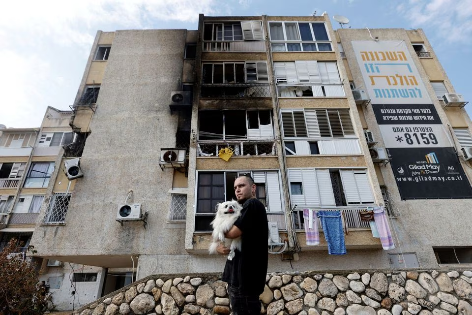 A man holds his dog after a rocket, launched from the Gaza Strip, landed in Ashkelon, southern Israel, October 11. PHOTO: REUTERS