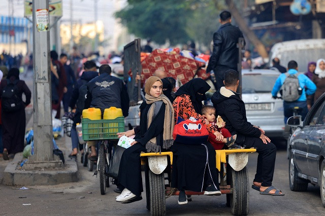 Palestinians ride in the back of a vehicle as they move toward safer areas following the resumption of Israeli strikes on Rafah in the southern Gaza Strip on December 1, 2023. PHOTO: AFP