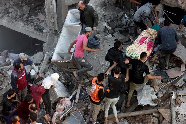Palestinian civlians and rescue teams remove a body from under the rubble following Israeli air strikes on the Rafah refugee camp in the southern Gaza Strip on December 1, 2023, after the expiration of a seven-day truce between Israel and Hamas. PHOTO: AFP