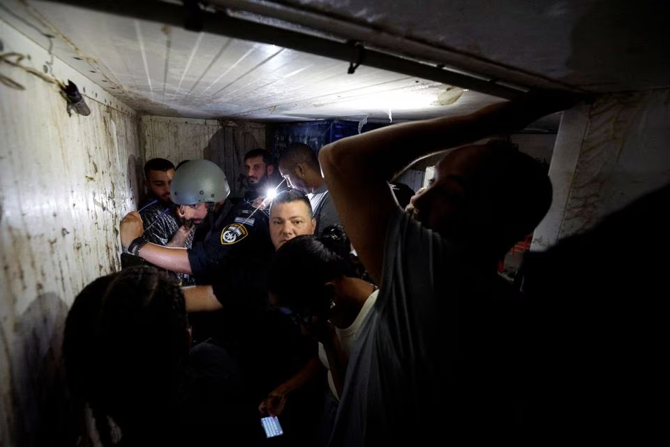 Israelis take cover in a bomb shelter while sirens sound as rockets from Gaza are launched towards Israel, in Ashkelon, southern Israel, October 11. PHOTO: REUTERS