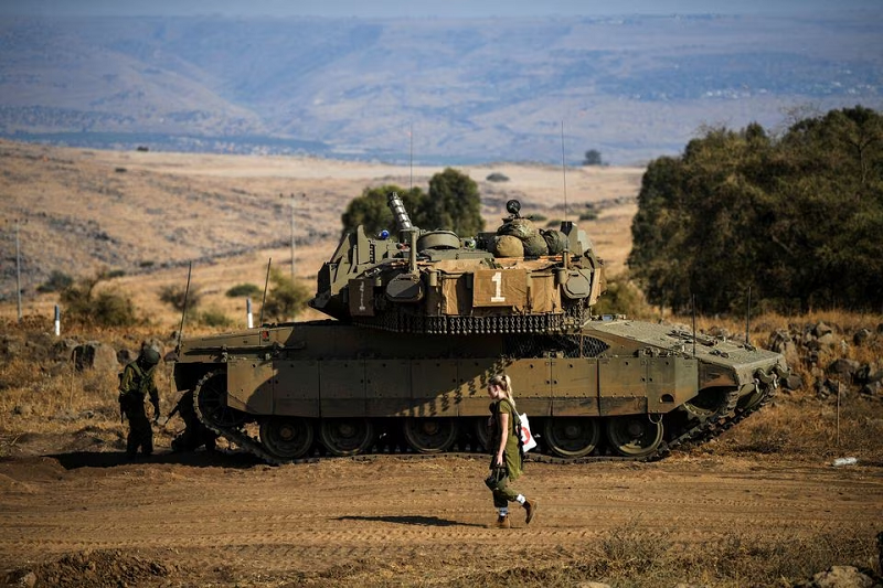 an israeli soldier walks past a tank as seen from the border with lebanon in northern israel october 14 2023 photo reuters