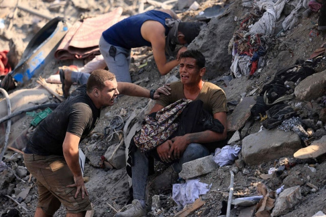 a man holds the remains of his mother wrapped in a blanket amid the rubble of building destroyed in an israeli strike on the bureij refugee camp in the central gaza strip on november 2 2023 photo afp