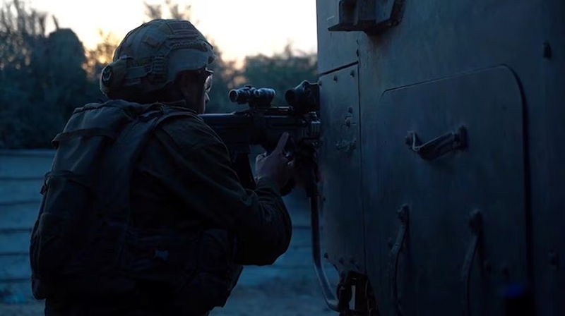 An Israeli soldier holds a weapon from behind a military vehicle in a location given as Gaza, October 30, 2023. PHOTO: REUTERS