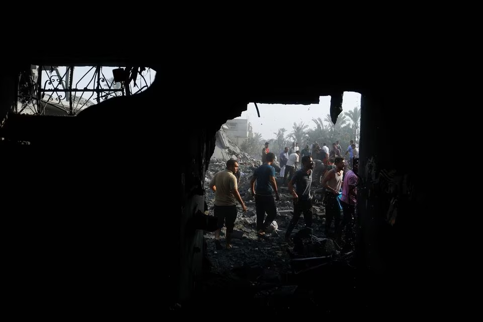 Palestinians gather on rubble in the aftermath of Israeli strikes, in Khan Younis in the southern Gaza Strip, October 11. PHOTO: REUTERS