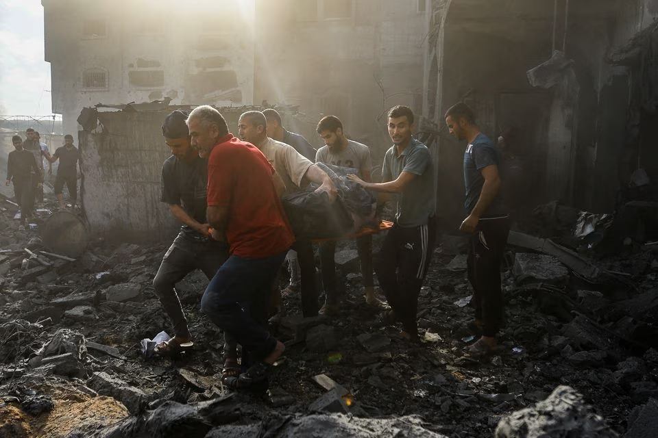Palestinians carry a casualty on rubble in the aftermath of Israeli strikes, in Khan Younis in the southern Gaza Strip, October 11. PHOTO: REUTERS