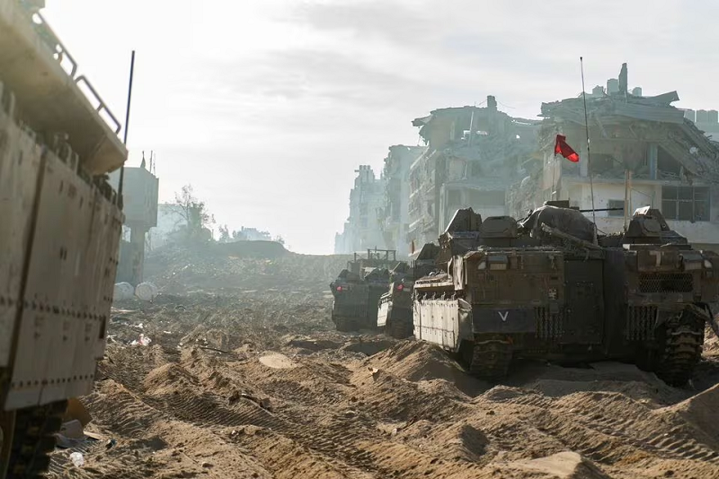 Israeli military vehicles next to damaged buildings in the Gaza Strip, in this handout image released November 18, 2023. PHOTO: REUTERS