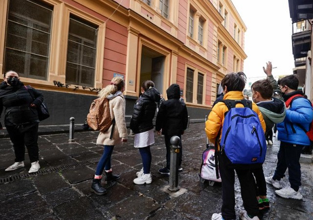 children stand outside a school as the town is downgraded from a red to an orange zone after weeks of tight restrictions to fight the coronavirus disease covid 19 outbreak in naples italy april 19 2021 photo reuters