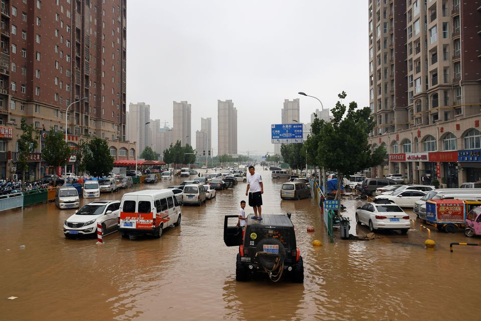 men stand on a vehicle on a flooded road following heavy rainfall in zhengzhou henan province china july 23 2021 photo reuters