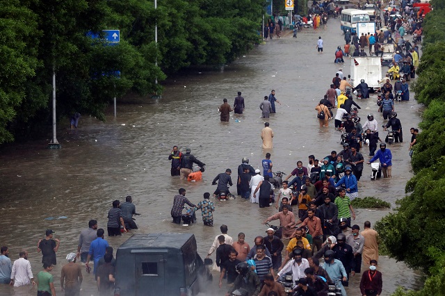 people wade through the flooded road during monsoon rain as the outbreak of the coronavirus disease continues in karachi photo reuters