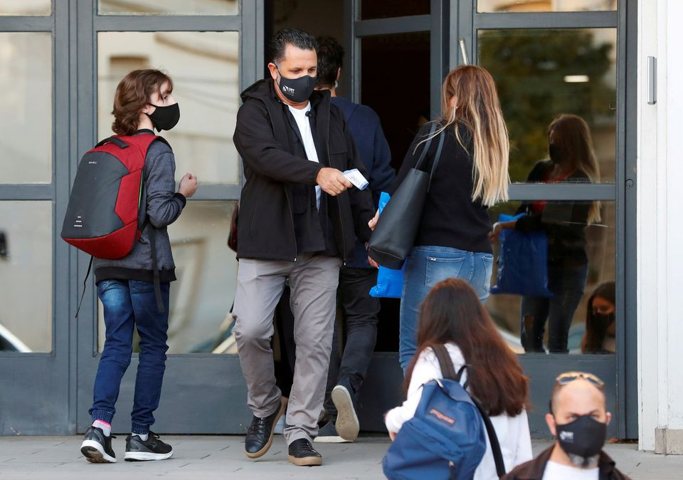 an employee checks the temperature of a woman at the entrance to a school amid a rise in coronavirus disease covid 19 cases in buenos aires argentina photo reuters