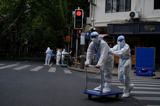 workers in protective suits work at a residential area under lockdown amid the coronavirus disease covid 19 pandemic in shanghai china april 17 2022 reuters workers in protective suits work at a residential area under lockdown amid the coronavirus disease covid 19 pandemic in shanghai china april 17 2022 reuters