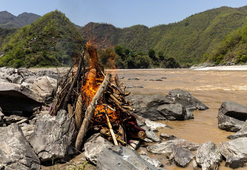 the burning pyre of pramila devi 36 who died from complications related to the coronavirus disease covid 19 is seen during her cremation on the banks of the river ganges in pauri garhwal in the northern state of uttarakhand india may 24 2021 devi s eldest daughter got married and moved away in late april after the family hosted a ceremony attended by over two dozen people her husband suresh kumar 43 told reuters two weeks after that devi suffered a bout of diarrhoea but it was not until 10 days later that kumar who has no income and depends on handouts took her to a nearby dispensary that has been turned into a small covid 19 facility with four beds devi tested positive for covid 19 with very low blood oxygen levels she died a day later reuters