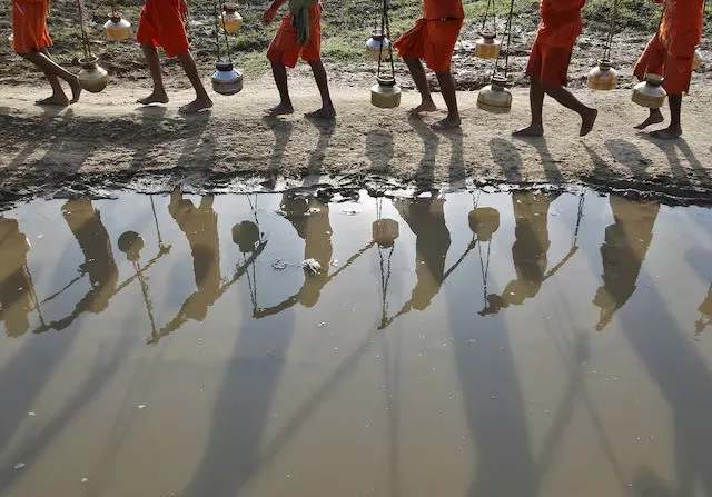 kanwarias or devotees of hindu god shiva carrying pitchers are reflected in a puddle as they walk after filling the pitchers with the water from the river ganges in allahabad india july 13 2015 photo reuters kanwarias or devotees of hindu god shiva carrying pitchers are reflected in a puddle as they walk after filling the pitchers with the water from the river ganges in allahabad india july 13 2015 photo reuters