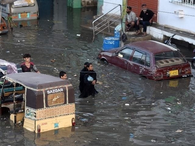 people wade through a flooded street after heavy monsoon rains in karachi on july 27 photo afp file