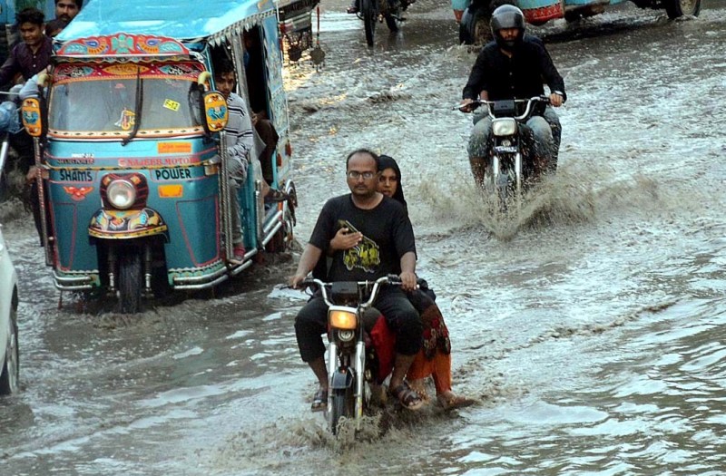 motorcyclists pass through rain water accumulated on the road during downpour on july 17 photo app