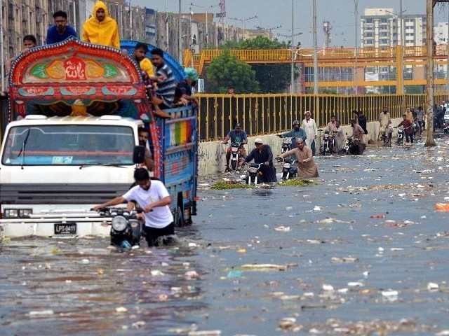 people wade through a flooded street after heavy monsoon rains in karachi photo afp file