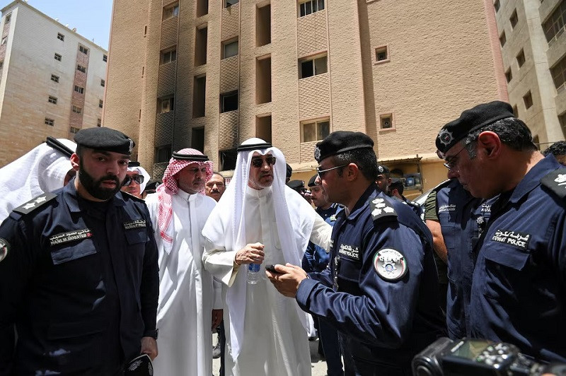 Kuwait's Deputy Prime Minister and Minister of Defense and acting Interior Minister, Fahad Yusuf Al-Sabah speaks with police officers in front of a burnt building, following a deadly fire, in Mangaf, southern Kuwait, June 12, 2024. PHOTO: REUTERS