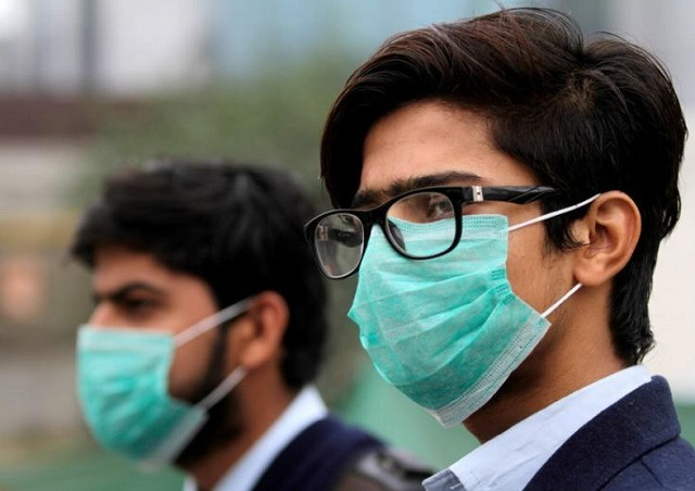 men wearing protective masks wait for a bus in lahore pakistan november 22 2019 photo reuters